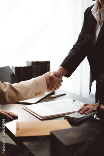 Foto Two professionals shake hands over contracts, cash and legal books on a desk, su