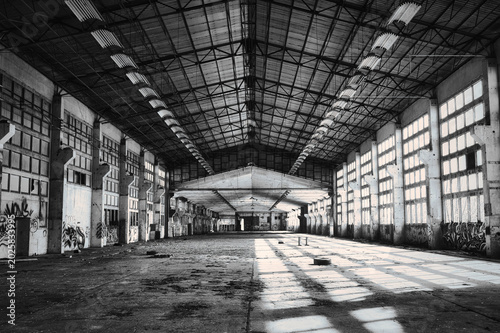Obraz na plátně Abandoned industrial factory hall in black and white with dramatic light - repor