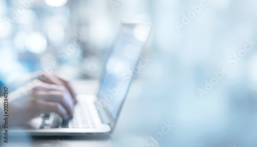Fotografija A close-up of hands typing on a laptop keyboard, showcasing a modern and minimalistic workspace setting with a blurred background