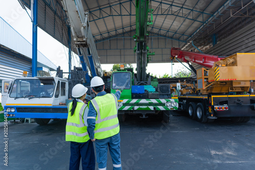 Cuadro en lienzo Engineers review mobile cranes in a maintenance shed during crane inspection, focusing on safety, equipment condition, lifting readiness, and worksite planning