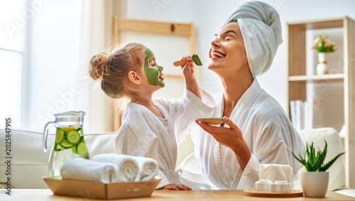 Mother and daughter enjoying spa day at home, bonding over skincare routine, wellness and relaxation in a cozy living room, suitable for promoting family time, health and beauty products