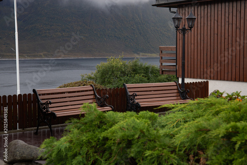 Two benches by the water in rainy weather