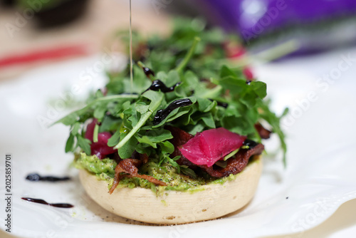Fresh arugula lettuce and pickled radish on a vegan english muffin drizzled with olive oil. A healthy and delicious vegetarian lunch.