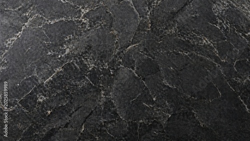 Abstract dark grey background with rough stone texture and subtle natural cracks on the surface