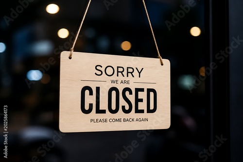 Closed sign hangs on a door indicating that the business is currently not open to customers temporarily.