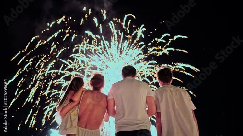 Parents with kids watch the beautiful fireworks on the ocean coast