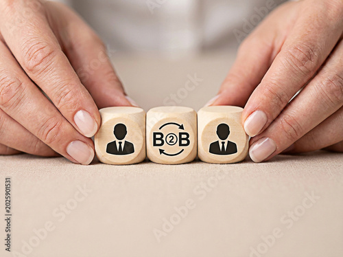 Hands arranging wooden blocks with b2b business icons to represent professional company to company connection