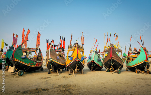 Symmetric front view of colorful traditional wooden moon fishing boats parked on sandy beach of Coxs Bazar Bangladesh. 
