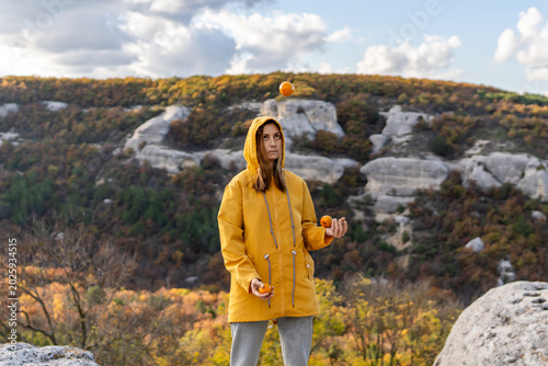 Obraz na plátne Juggling woman oranges concentrating on throwing fresh fruit on a rocky cliff du
