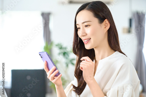 Φωτογραφία 自宅でスマホを見る笑顔の女性