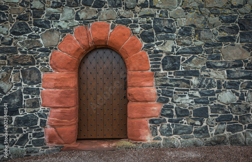 Detail of a weathered sandstone wall with a door.
