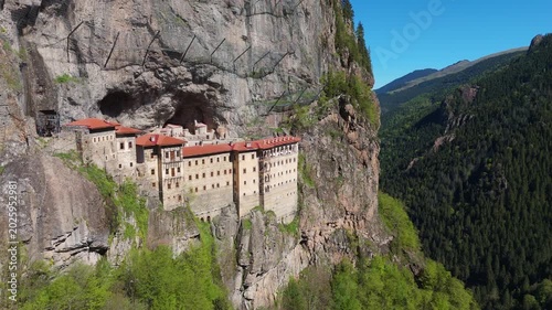 Sumela Monastery, Trabzon. Drone view of the historic white stone structure with a red tile roof clinging tightly to a steep rock wall above a green valley Turkey travel destination 