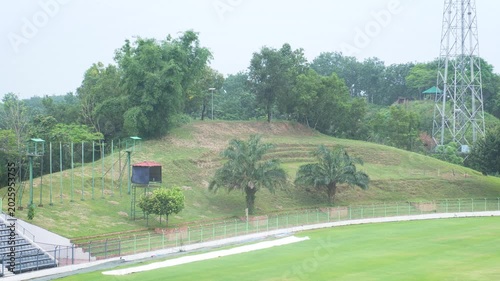Natural green hill gallery with lush trees and steel tower at sports facility