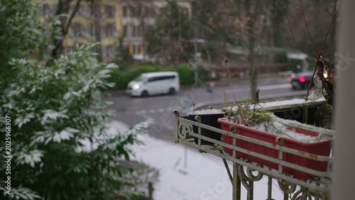 Photos Snow falling on residential street seen from balcony with flower planter, calm w