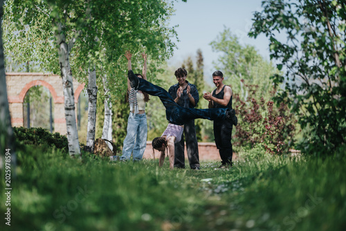 Foto Teenagers perform an acrobatic cartwheel while friends watch and clap in a park