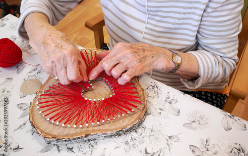 Slika na platnu Close-up detail of an elderly woman’s hands shaping a heart from cotton by hand