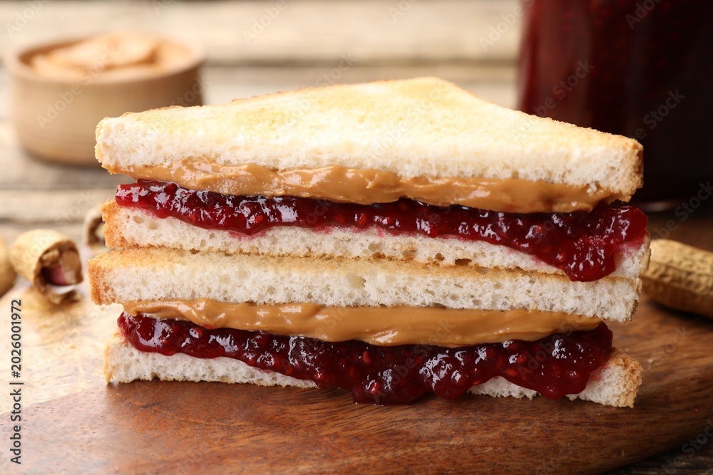 Fototapeta premium Tasty sandwiches with peanut butter, jam and nuts on table, closeup