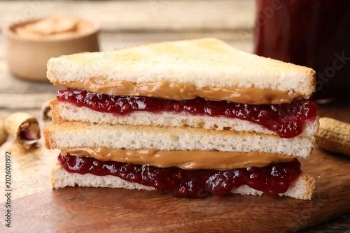 Fototapeta Tasty sandwiches with peanut butter, jam and nuts on table, closeup