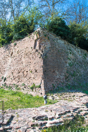 Un tratto ad angolo della cinta muraria di Ferrara con degli alberi che crescono sulla cima
