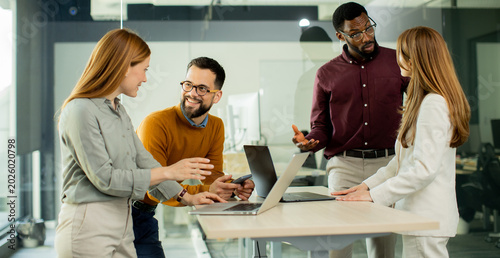 Group of people discussing ideas and working on laptops in a modern office space