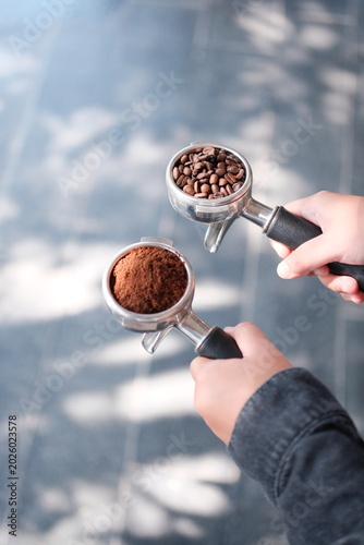 Φωτογραφία Person holding coffee tamper with ground and whole beans outdoors