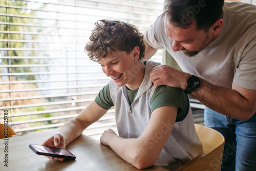 Φωτογραφία Father supporting teenage son at home during everyday moment.