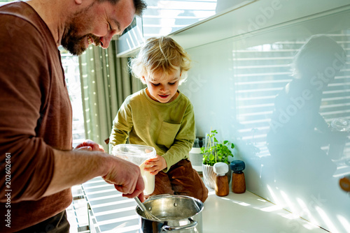Foto Dad and toddler preparing simple meal together in bright kitchen.