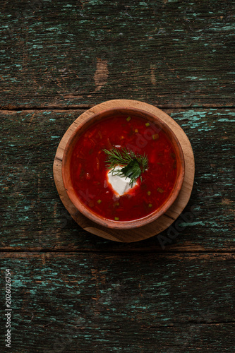 Traditional Ukrainian borscht soup with sour cream and dill in a clay bowl
