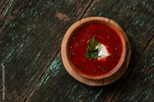 Traditional Ukrainian borscht soup with sour cream and dill in a clay bowl
