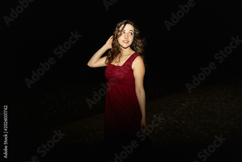 Night portrait of woman in red dress with flash lighting