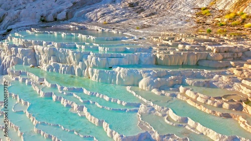 Aerial view of Travertines of Pamukkale, Turkey. Natural thermal pools and blue water steps flow through white limestone terraces.