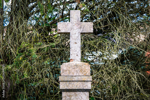 Una croce di marmo in un cimitero con degli alberi sullo sfondo 