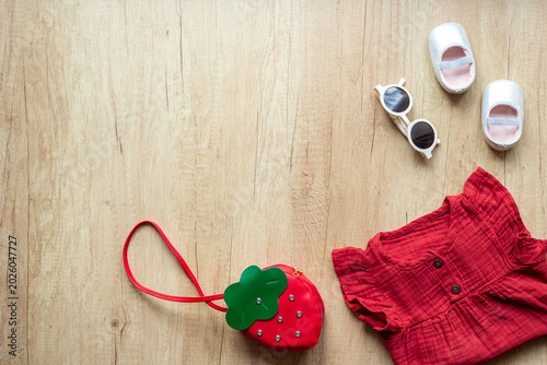 Bild auf Leinwand Baby girl red cotton muslin dress with strawberry-shaped handbag and shoes, top view