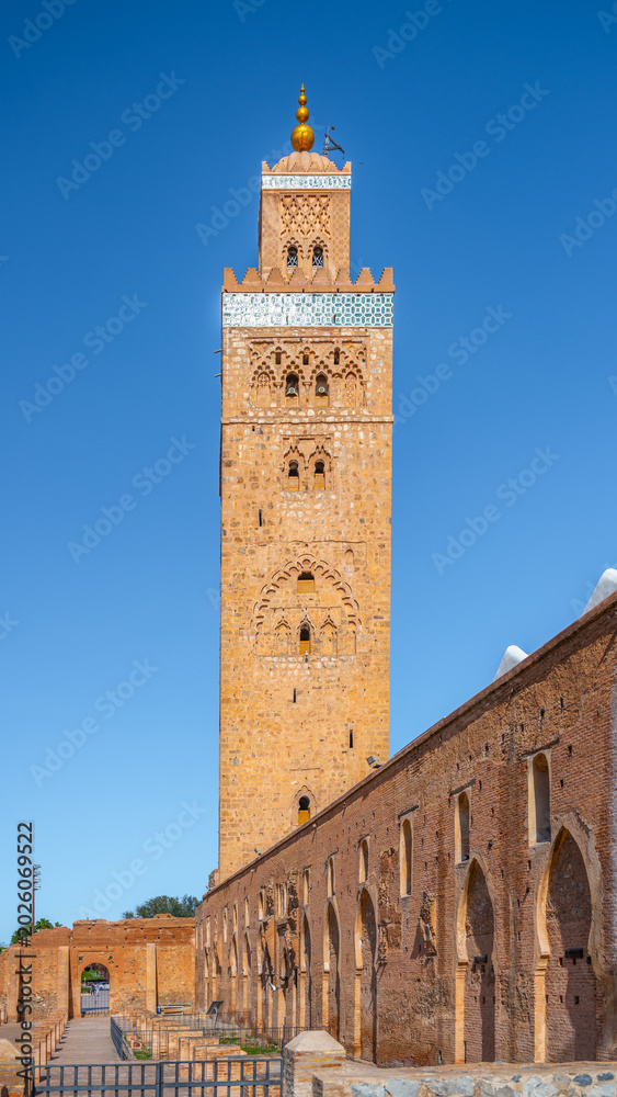 Obraz premium Kutubiyya Mosque is the largest mosque in Marrakesh, Morocco. Visitors can see its tall minaret and surrounding architecture during the day. Many people come to admire its design.