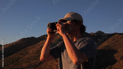 A man taking a photo from a scenic viewpoint at sunset