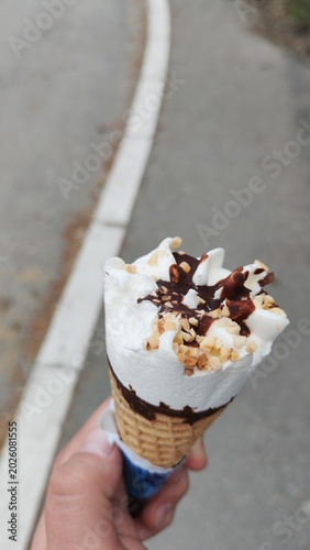 A hand holding a scoop of ice cream. Close-up summer lifestyle scene with a refreshing dessert on a warm day.