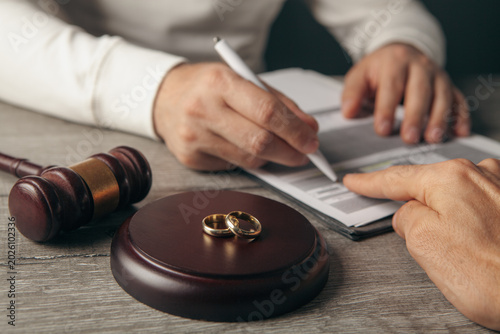 Wedding rings and gavel on divorce decree, closeup