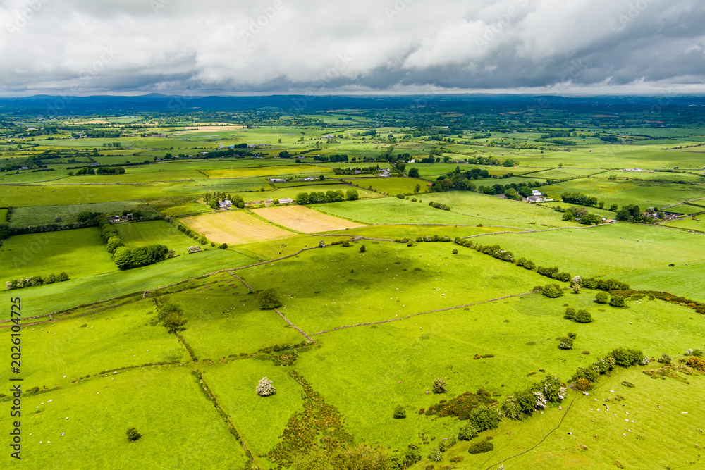 Obraz premium Patchwork fields spread across County Meath, Ireland, under heavy cloud. A peaceful Boyne Valley farming landscape of hedgerows, pasture and rural roads.