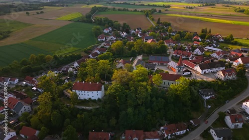 Aerial footage of Inkofen in Oberbayern, Germany, with panoramic views of Schloss Inkofen, church tower and the green Amper riverbank landscape.