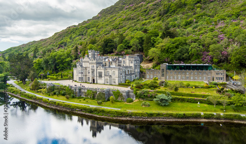 Aerial view of Kylemore Abbey beside Pollacappul Lough in Connemara, County Galway, Ireland. The estate sits between lake, woodland and mountain slopes.