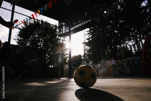 Low Angle Silhouette of Soccer Ball on Outdoor Court with Sun Flare