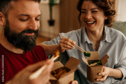 Foto Couple laughing, enjoying takeout food at home