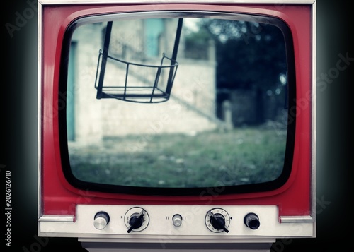 Vintage red television displaying eerie swing set scene with unsettling atmosphere. Retro TV screen shows haunting playground imagery. For horror, thriller, and nostalgic suspense concepts.
