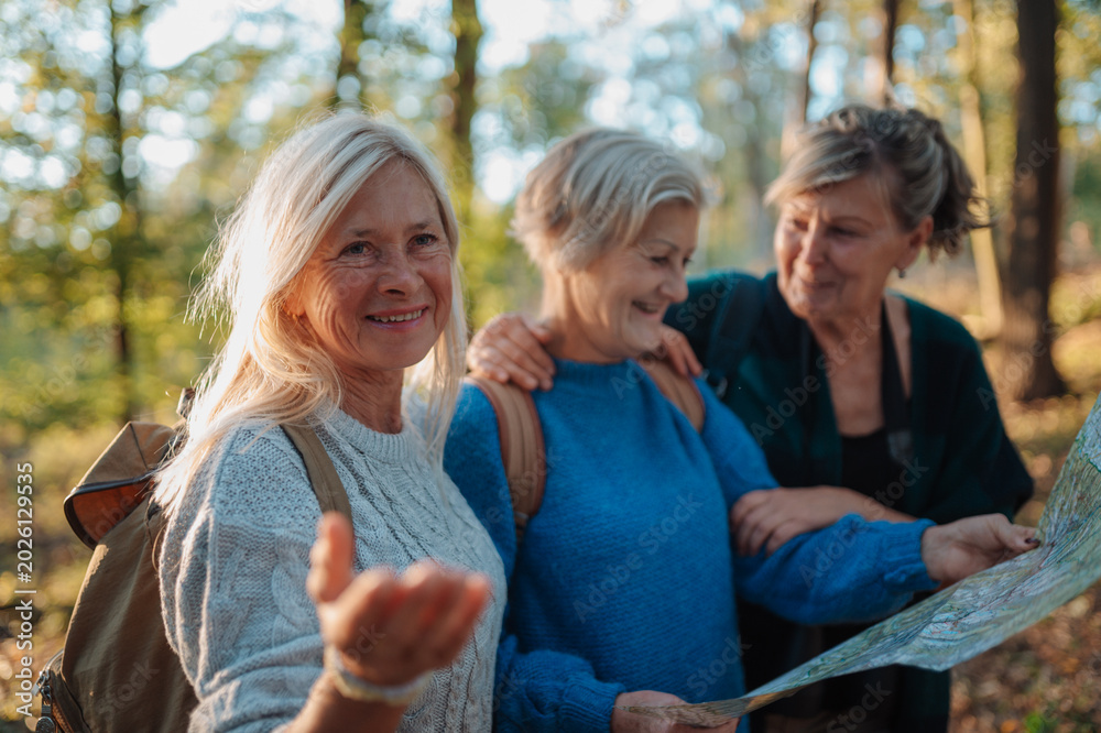 Fototapeta premium Mature female friends exploring nature together with map on hiking trip.