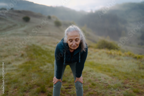 Fotografia Older runner resting after morning run in nature, catching breath