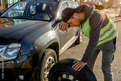 Transportation, traveling concept. Worker changes a broken wheel of a car. The driver should replace the old wheel with a spare. Man changing wheel after a car breakdown.