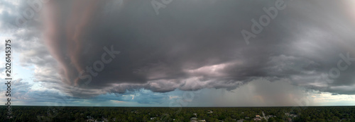 Dark stormy clouds forming on gloomy sky before heavy rainfall over suburban town area