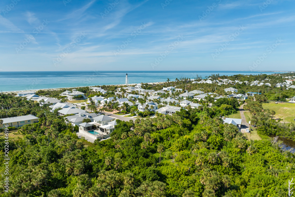 Fototapeta premium Expensive mansions between green palm trees on Gulf of Mexico shore in island small town Boca Grande on Gasparilla Island in southwest Florida, USA. Aerial view of wealthy waterfront neighborhood