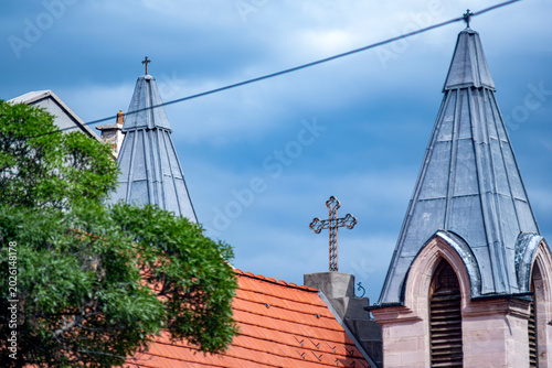 Fotografie Detailed view of Gothic church steeples and an ornate metal cross against a moody blue sky