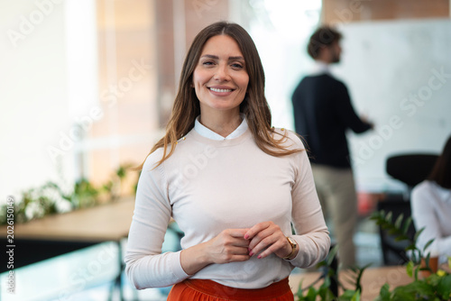 Smiling confident businesswoman standing in modern office environment